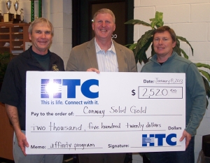 Chuck Jordan (left), Athletic Director for Conway High School Athletics, and Dennis Brown (right), Conway Solid Gold President, receive $2,520 check from Brent Groome (center), Chief Executive of Customer Operations at HTC.  